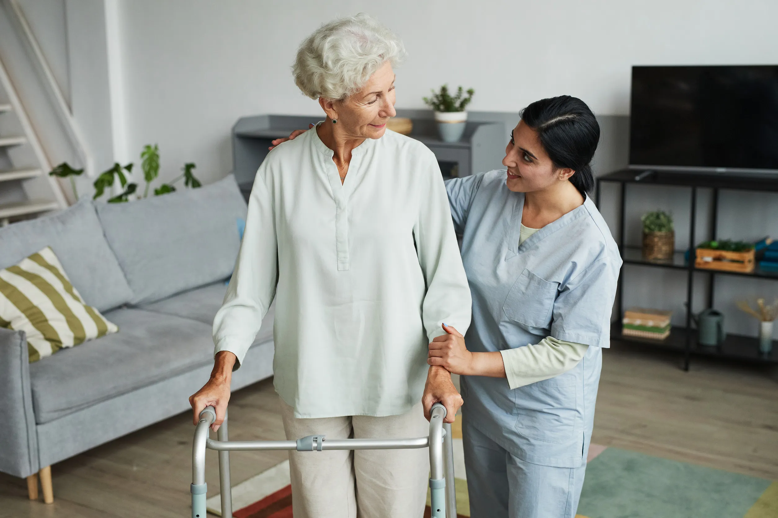 Waist up portrait of smiling female nurse helping senior woman using mobility walker in retirement home, copy space Waist up portrait of smiling female nurse helping senior woman using mobility walker in retirement home, copy space